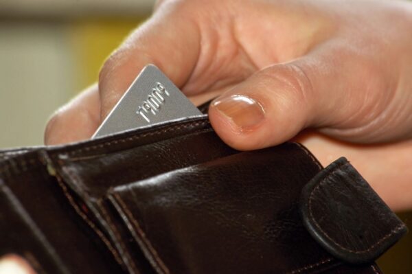 A person holding an open wallet with one card in it.