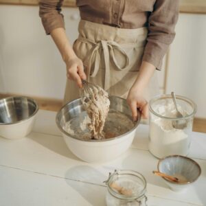 Person mixing dough in a kitchen bowl.
